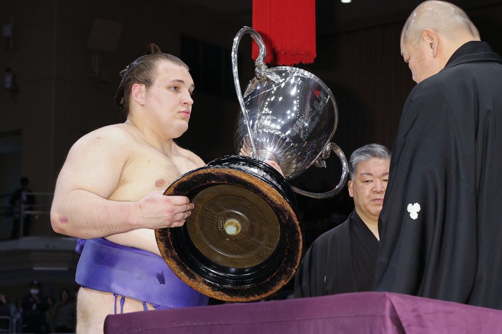 El luchador ucraniano sekiwake Aonishiki recibe la Copa del Emperador del jefe de la Asociación de Sumo de Japón, Hakkaku, después de ganar el Gran Torneo de Sumo de Kyushu de 15 días en Fukuoka, Japón, el 23 de noviembre de 2025. (Fuente: Getty Images)