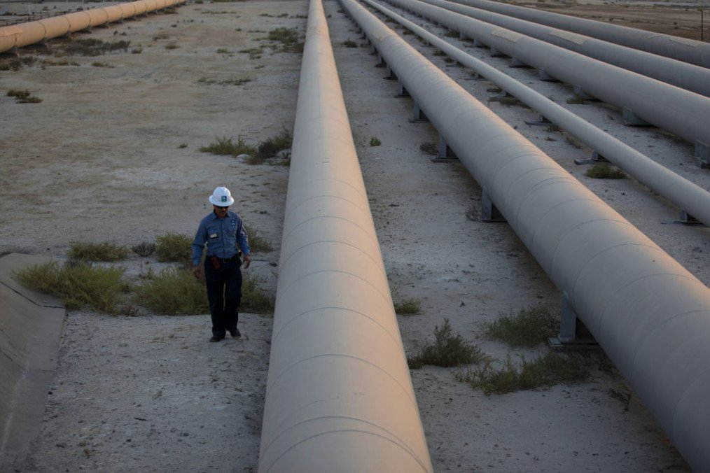 An employee walks along a pipeline carrying crude oil from the Juaymah Tank Farm in Saudi Aramco’s Ras Tanura oil refinery and oil terminal in Ras Tanura, Saudi Arabia, on October 1, 2018. (Source: Getty Images)