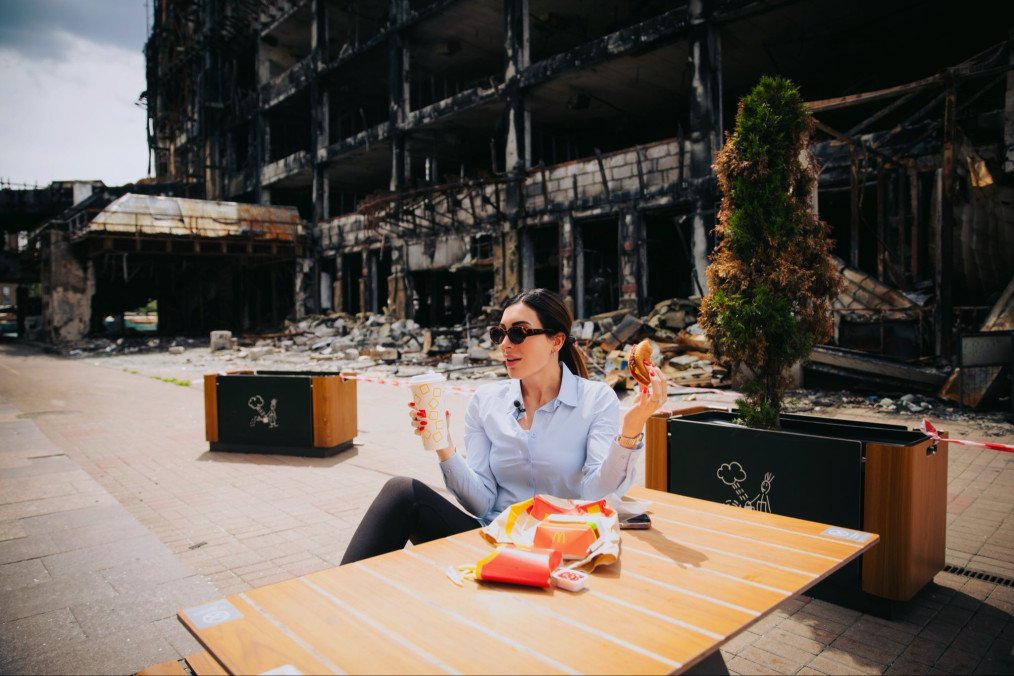 Political commentator Laura Loomer eats McDonald’s at an outdoor table in Kyiv with a blast-damaged building in the background. (Source: X / Laura Loomer) Political commentator Laura Loomer eats McDonald’s at an outdoor table in Kyiv with a blast-damaged building in the background. (Source: X / Laura Loomer)