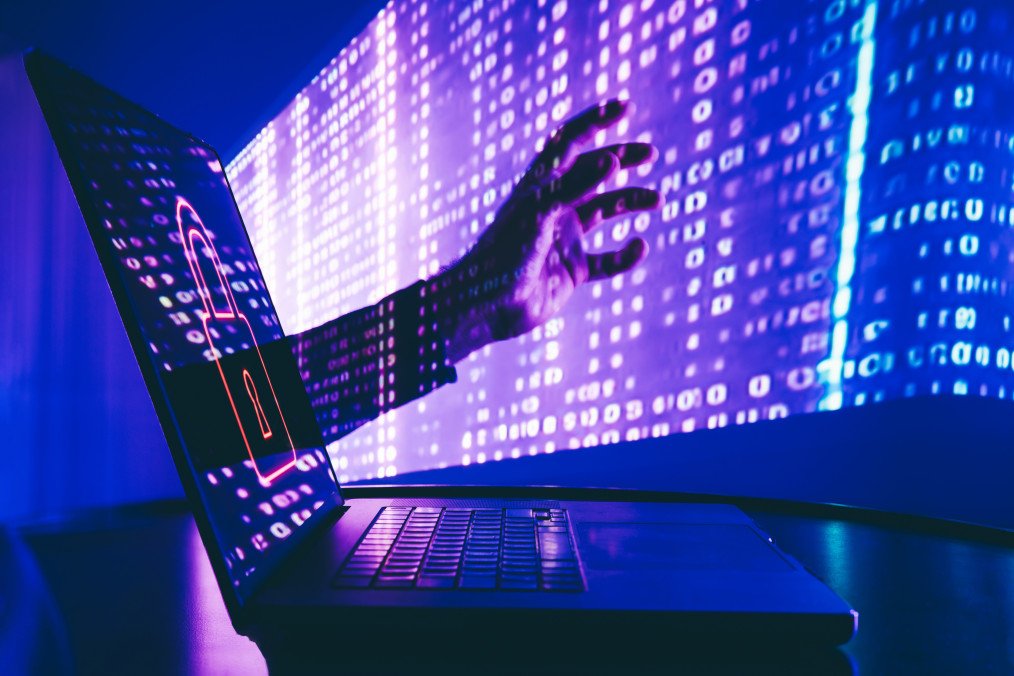A visual representation of a cyberattack, with binary code projected on a hand reaching towards a laptop. Illustrative photo. (Source: Getty Images)