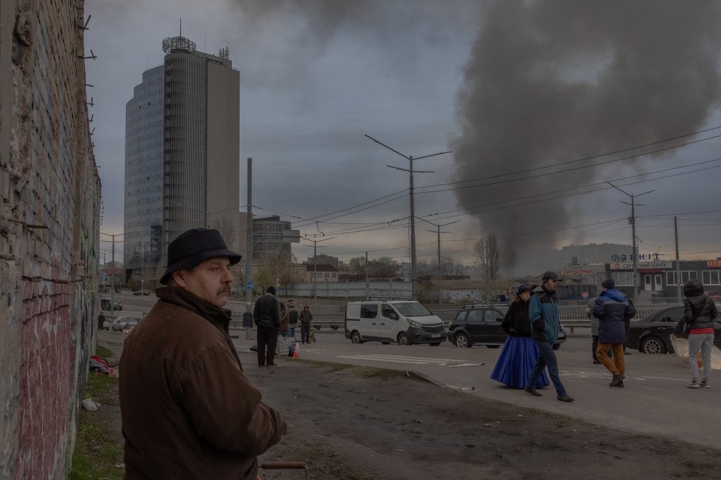 KYIV, APRIL 6, 2025: Smoke rises in the distance as people walk through a flea market in Kyiv, Ukraine, following a Russian missile attack on the capital. (Photo: ROMAN PILIPEY via Getty Images)
