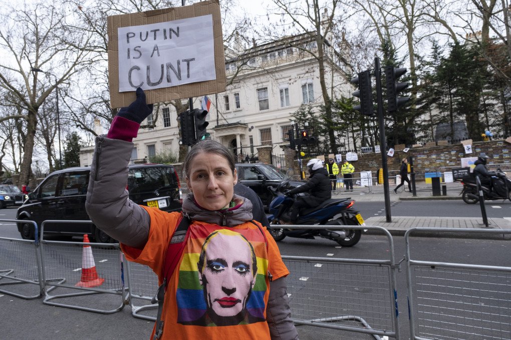 Protester with a profane sign wearing a t-shirt of Vladimir Putin as a character wearing make-up on an LGBT rainbow flag outside the Russian embassy on 28th February 2022 (Source: Mike Kemp via Getty Images) Protester with a profane sign wearing a t-shirt of Vladimir Putin as a character wearing make-up on an LGBT rainbow flag outside the Russian embassy on 28th February 2022 (Source: Mike Kemp via Getty Images)
