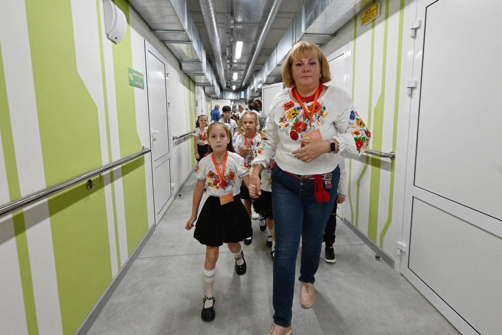 A teacher and children walk down a corridor during the first day of the new school year at an underground school in Kharkiv on September 1, 2025. Photo: SERGEY BOBOK/AFP via Getty Images