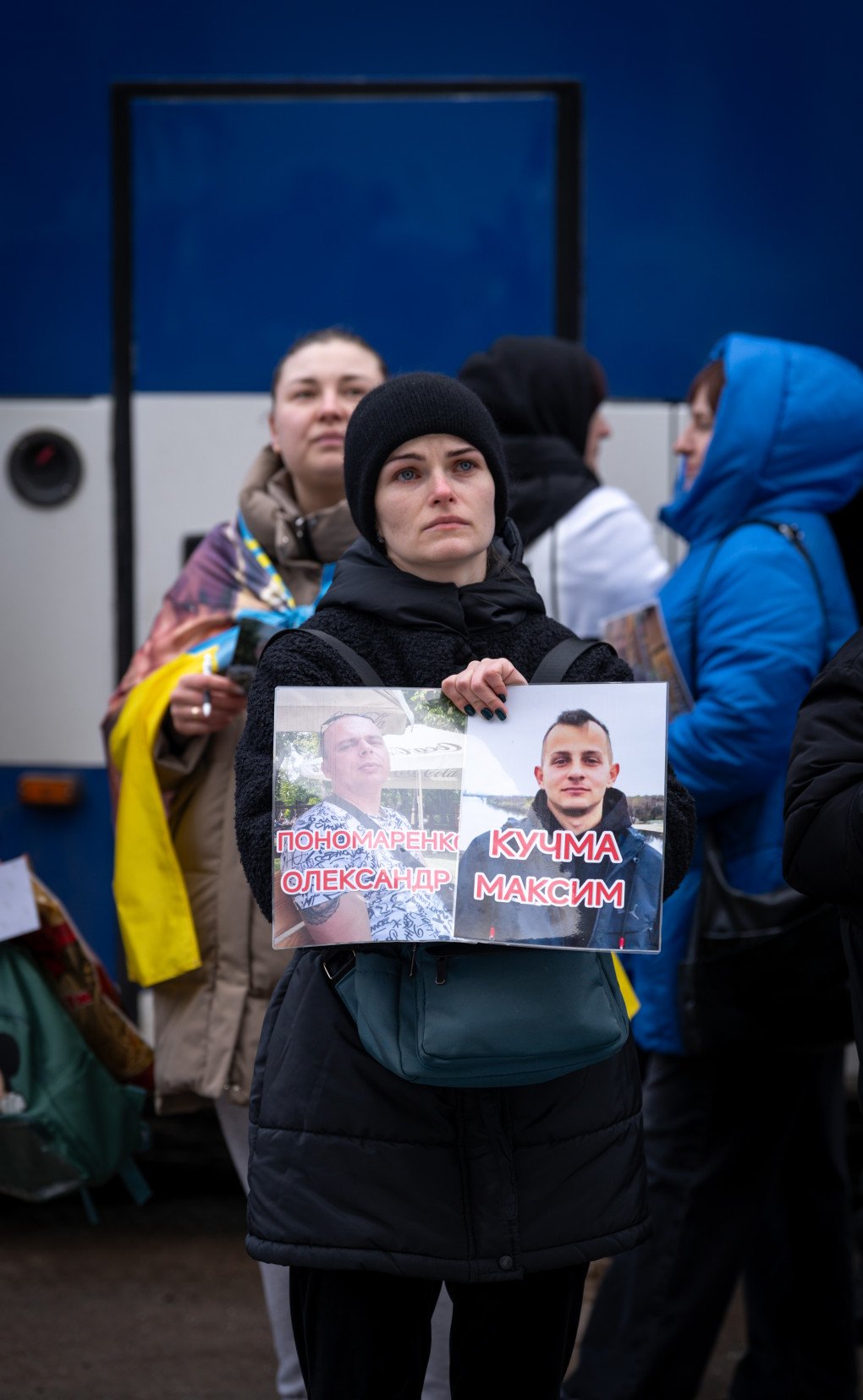 A woman stands holding the photos of two of her loved ones during the first day of the exchange, March 5, 2026, undisclosed location, Ukraine. Photo by Dmytro Ivanov/UNITED24 Media