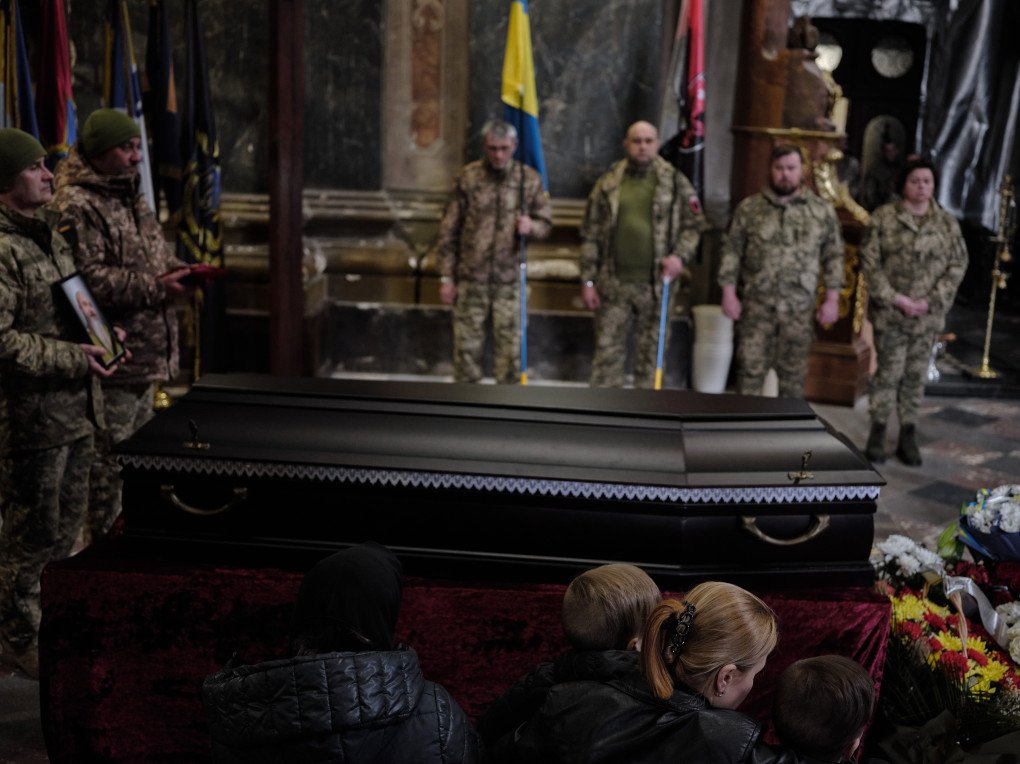 A mother and her two sons sit in mourning in front of the coffin of their husband and father, as his fellow soldiers stand in solemn tribute beside the coffin of their fallen comrade at Sts. Peter and Paul Garrison Church. April 2025. A mother and her two sons sit in mourning in front of the coffin of their husband and father, as his fellow soldiers stand in solemn tribute beside the coffin of their fallen comrade at Sts. Peter and Paul Garrison Church. April 2025.