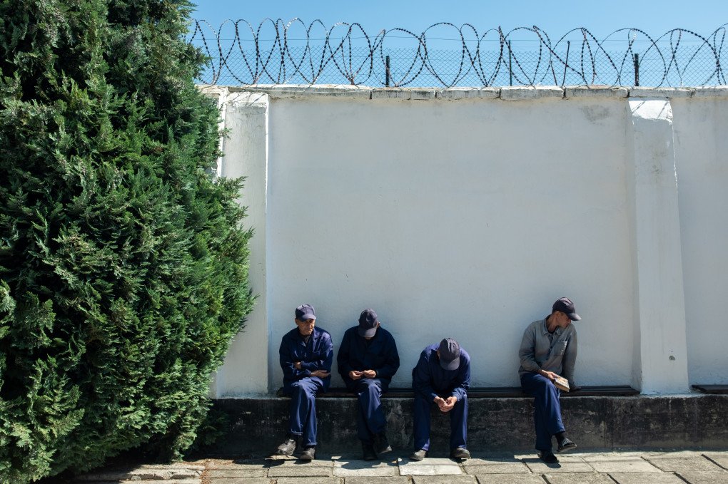 Russian POWs sit in the yard of a Ukrainian camp during a break, under barbed-wire walls. Photo: Andrii Ovod/UNITED24 Media
