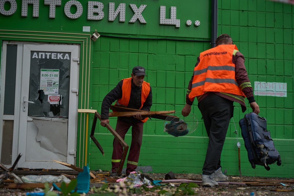 Trabajadores municipales retiran los escombros frente a una farmacia dañada en el distrito Shevchenkivskyi de Kyiv tras el ataque ruso nocturno con drones y misiles el 7 de mayo de 2025.