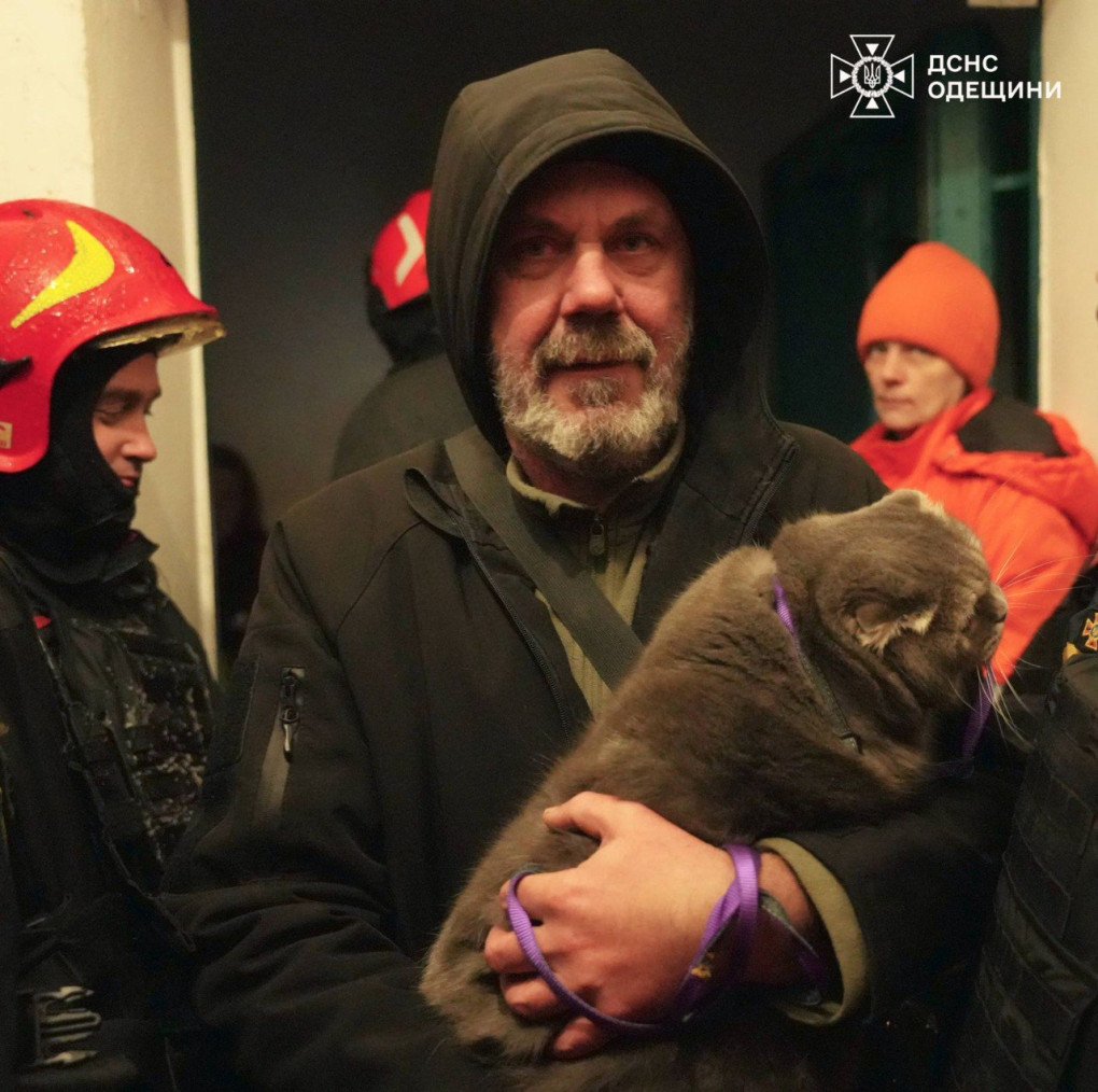 A resident holds a rescued cat after being evacuated from a building hit during Russia’s overnight attack on Odesa. (Source: State Emergency Service)