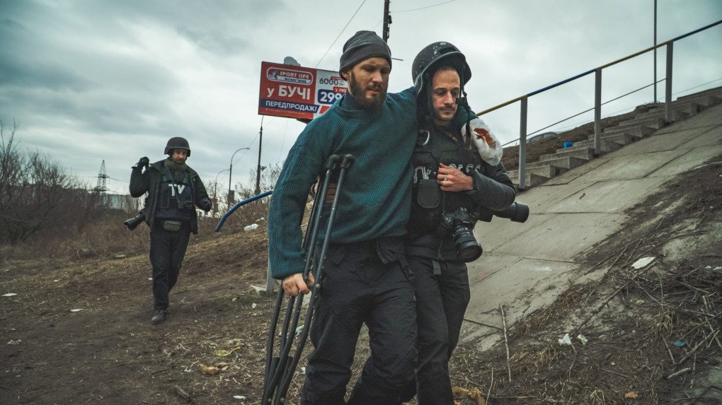 Antoni Lallican ayuda a un hombre herido a cruzar el puente de Irpin. Marzo de 2022. Foto: Adrien Vautier