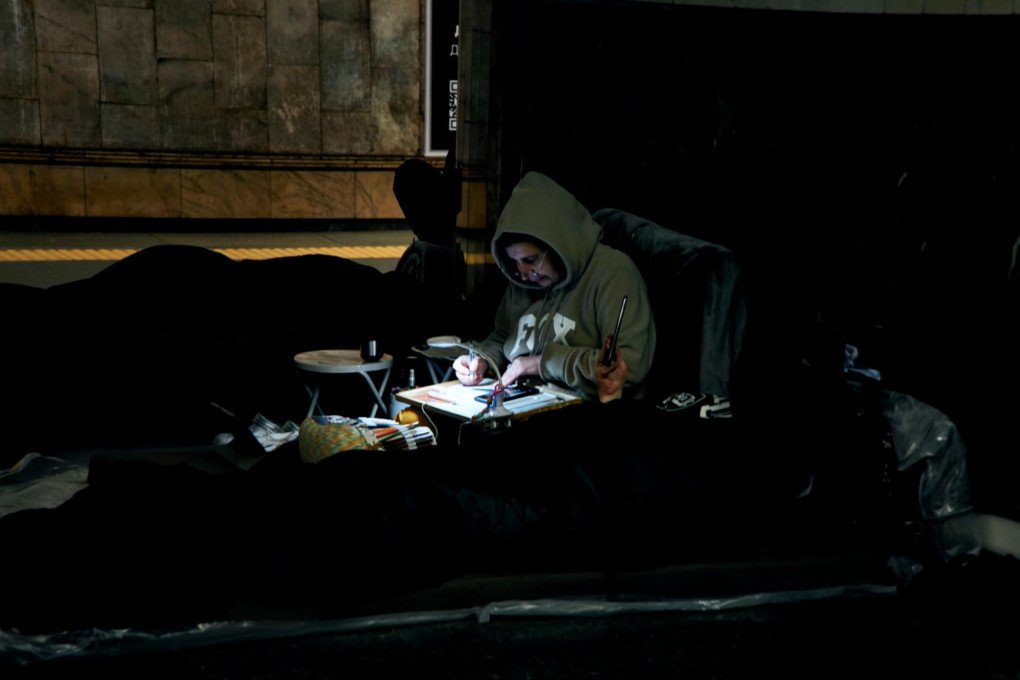 A Kyiv woman takes shelter in a metro station, tens of meters underground, and draws on a small desk. Kyiv, Ukraine, October 6, 2026 (Photo: Louis Beaudemont/UNITED24 Media)
