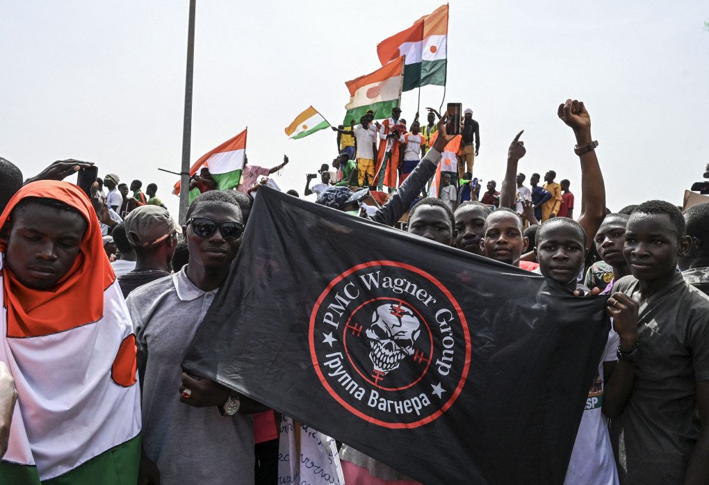 Men hold a flag bearing the logo of Wagner outside the Niger and French airbase in Niamey on September 2, 2023 (Source: AFP via Getty Images) Men hold a flag bearing the logo of Wagner outside the Niger and French airbase in Niamey on September 2, 2023 (Source: AFP via Getty Images)
