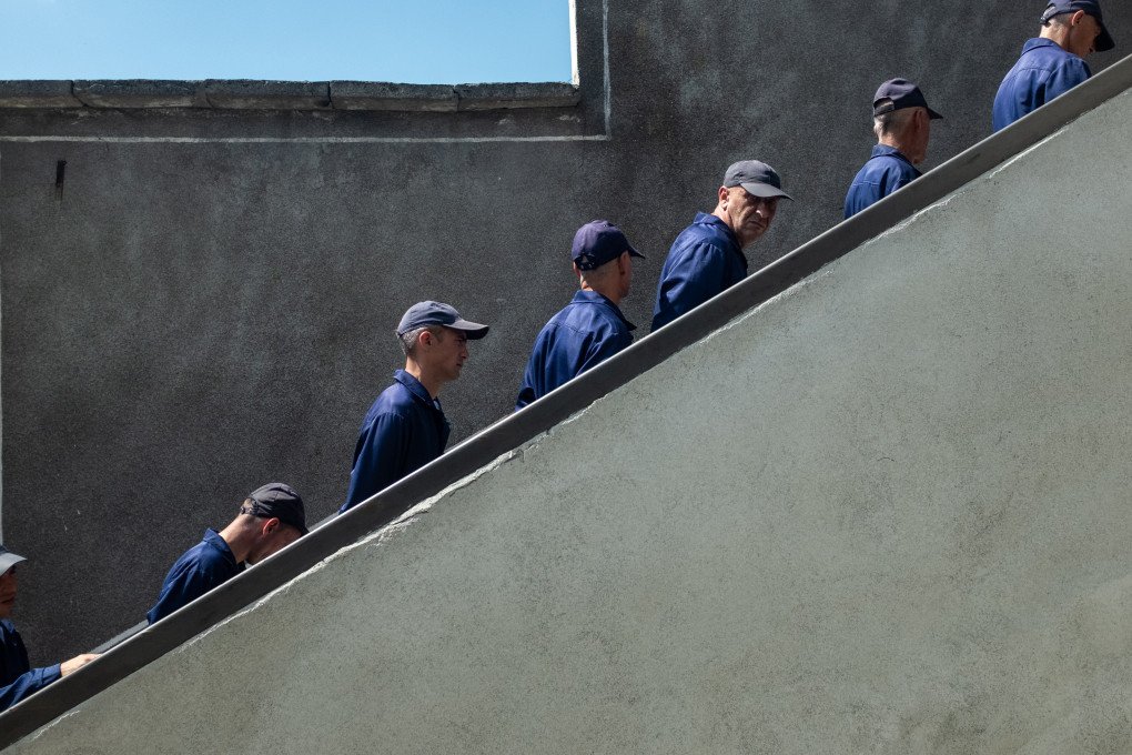 Prisoners of war in blue uniforms walk in line inside a Ukrainian detention facility. Photo: Andrii Ovod/UNITED24 Media