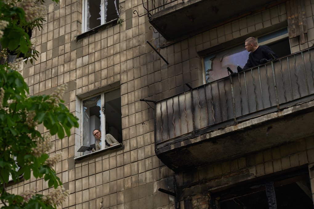 Habitantes de Kyiv miran a través de ventanas rotas y balcones chamuscados tras un ataque ruso con misiles balísticos y drones contra la capital el 7 de mayo de 2025.