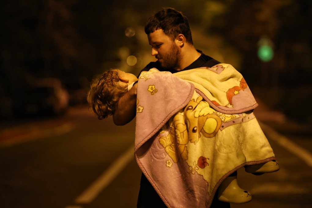 A man carries a child after a Russian drone-and-missile attack on July 31, 2025, in Kyiv, Ukraine. (Source: Getty Images)
