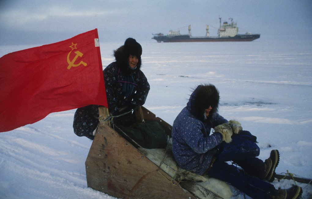 Residentes de Barrow, Alaska, viajan en un trineo con una bandera soviética mientras pasa el carguero rompehielos soviético Vladimir Arsenev. (Fotografía de: Bill Roth vía Getty Images) Residentes de Barrow, Alaska, viajan en un trineo con una bandera soviética mientras pasa el carguero rompehielos soviético Vladimir Arsenev. (Fotografía de: Bill Roth vía Getty Images)