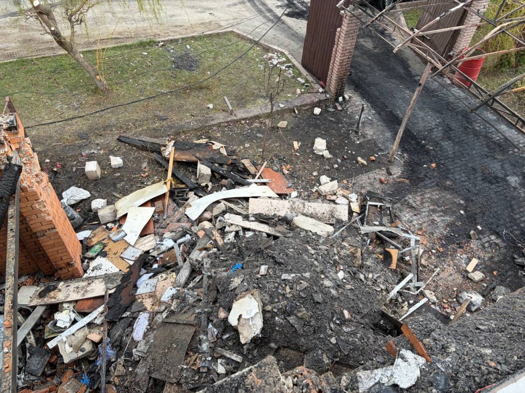 A view from above showing a massive pile of charred rubble, collapsed roofing, and destroyed belongings scattered across the yard of the targeted residence. (Source: Serhiy “Flash” Beskrestnov)