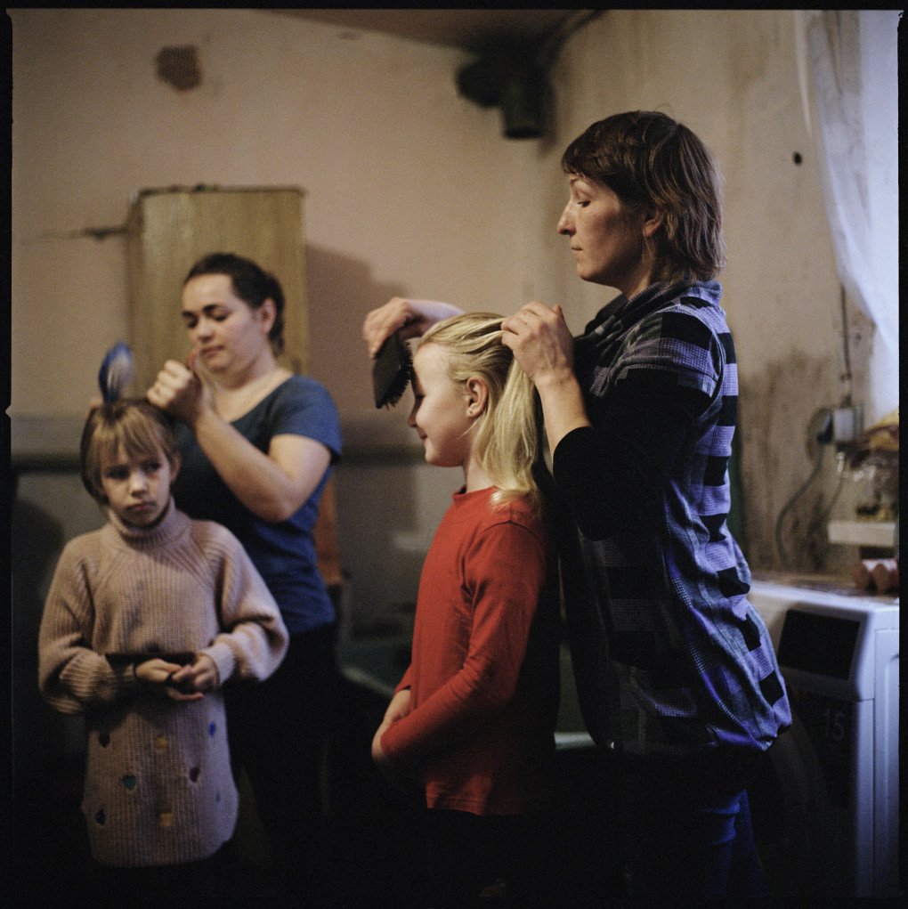 Olha Hrynyk (right) combing Myroslava’s hair and Hanna Drobysh (left) combing her daughter Angelina’s hair in their kitchen in the Poltava region, 2022.From the series 5K from the Frontline. (Image: Anastasia Taylor-Lind) Olha Hrynyk (right) combing Myroslava’s hair and Hanna Drobysh (left) combing her daughter Angelina’s hair in their kitchen in the Poltava region, 2022.From the series 5K from the Frontline. (Image: Anastasia Taylor-Lind)