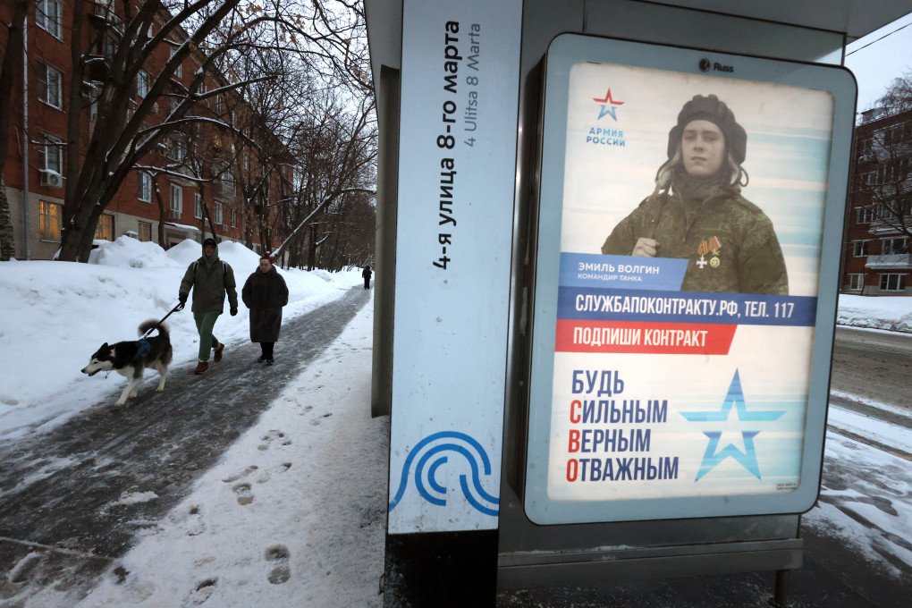Passerby with dog walk next to a military propaganda poster, primoting a contarct service in Russian Armed Forces and depicting tank commander Emil Volgin, a participant in the armed invasion of Ukraine, on February 27, 2026, in Moscow, Russia. The caption reads: "Sign a contract! Be strong, faithful and brave". (Photo by Contributor via Getty Images)