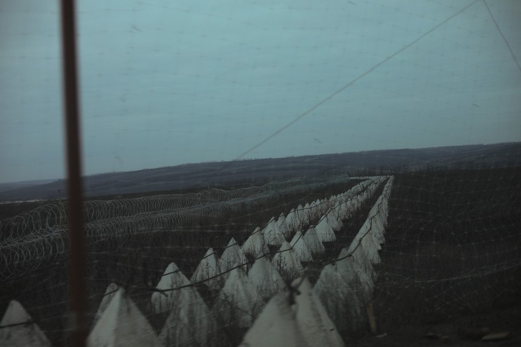 Barreras antitanque y alambre de púas bordean una carretera en el frente oriental de Ucrania, vistas a través de una red antidrones, parte de grandes fortificaciones defensivas. (Foto: Lucile Brizard/UNITED24 Media) La zona de la muerte