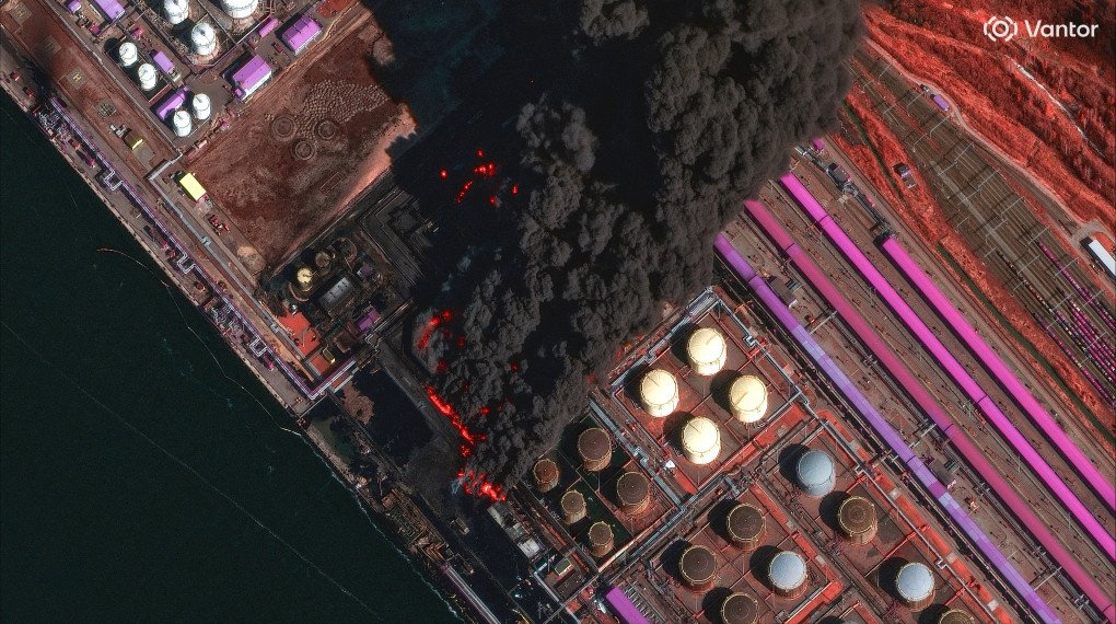 Satellite image shows large fire burning multiple oil storage tanks at Ust-Luga oil terminal complex with thick black smoke drifting east. (Source: Vantor)