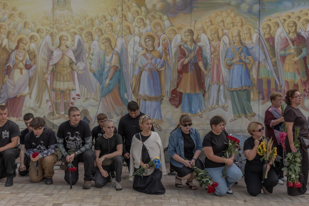 Mourners kneel down during a funeral ceremony for Ukrainian serviceman Danylo Smyrnov, callsign "Surfer", a member of the International Legion of Ukraine's Defence Intelligence who was recently killed in action, at the Saint Michael's Golden-Domed Monastery in Kyiv on September 3, 2026. (Photo by Roman Pilipey via Getty Images)