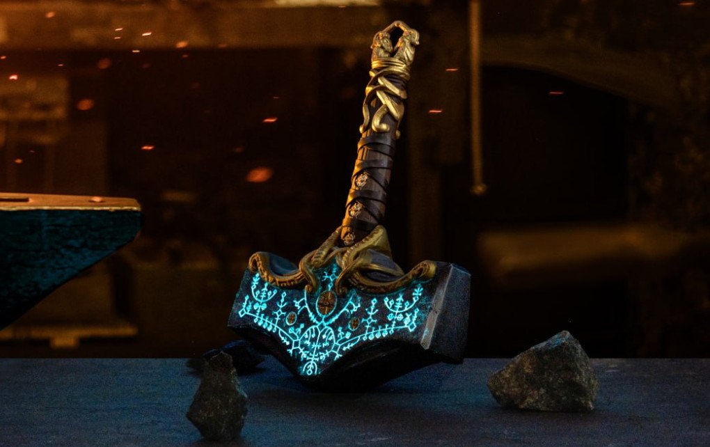 Réplica artesanal del Mjölnir de Thor de God of War: Ragnarök, con runas azules brillantes y un intrincado trenzado de estilo nórdico en el mango. (Fuente: Ancient Smithy)