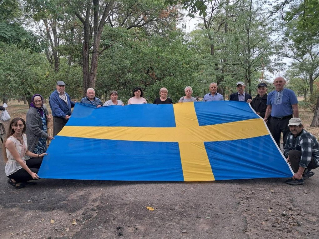 Residents of Zmiivka pose with a Swedish flag gifted by the King of Sweden in 2008. The flag was preserved by the village mayor during the eight-month Russian occupation. ((Photo: Facebook/ Svitlana Zalishchuk) 