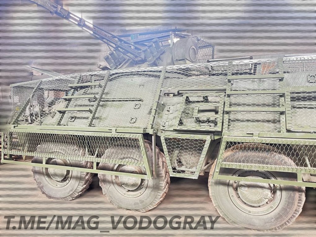 Side view of a BTR with mounted anti-drone grids, showing reinforced mesh protection along the wheels and hull. (Source: Telegram/MAG_VODOGRAY)