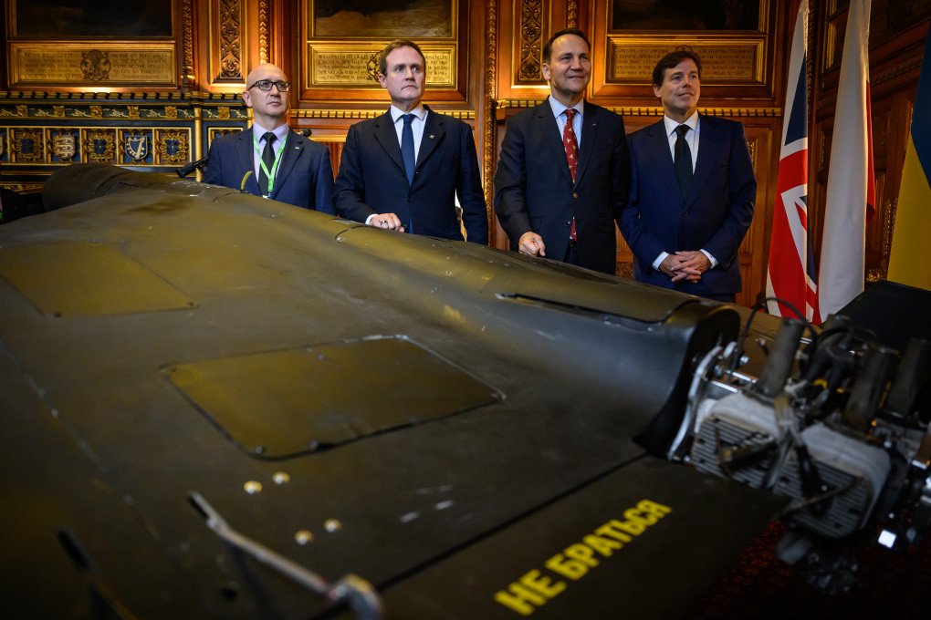 Eduard Fesko, Tom Tugendhat, Radek Sikorski, and Mark D. Wallace pose with a downed Iranian-made Shahed-136 drone displayed at the UK Parliament in London, October 14, 2025. (Source: Getty Images)
