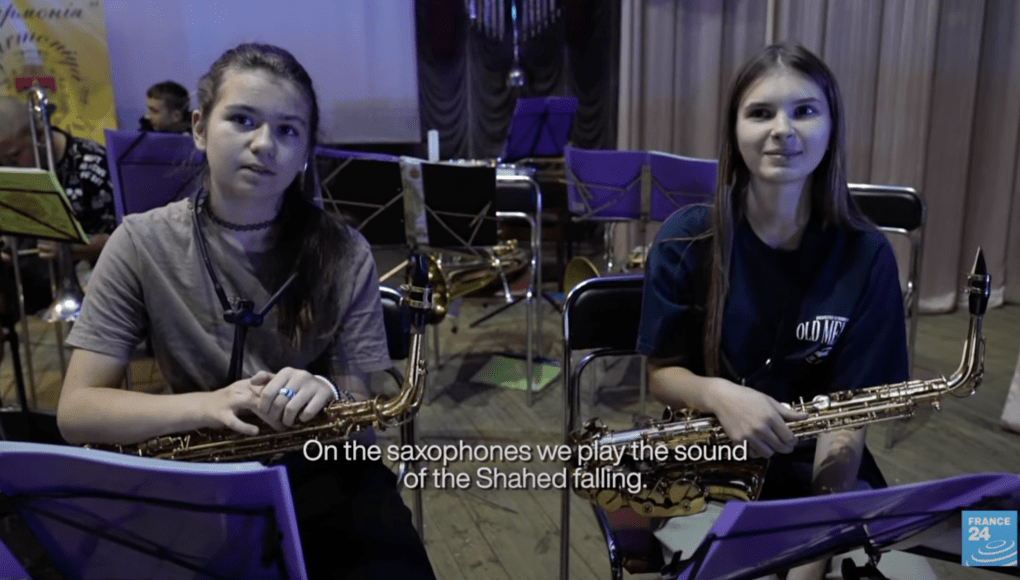 Jóvenes músicos de la orquesta juvenil Harmonia ensayan una pieza que imita el sonido de un dron Shahed al caer. (Fuente: France 24)