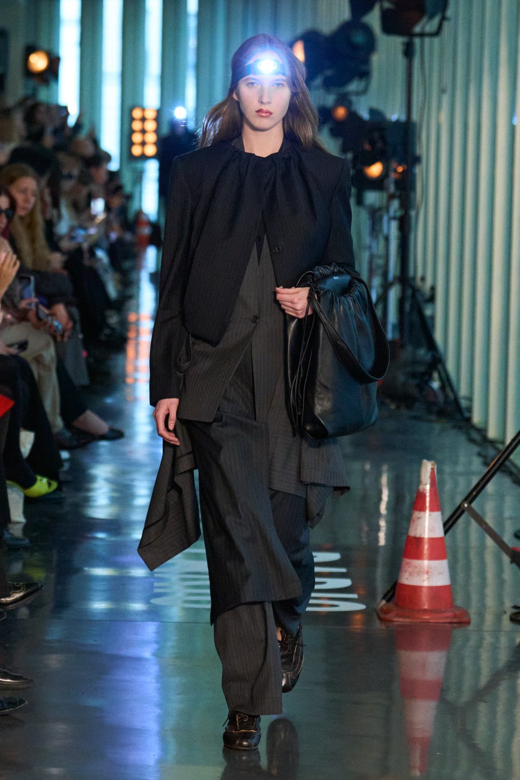 A model walks the runway in a sharp, pinstriped suit with oversized, flowing layers, showcasing a bold fusion of sophistication and avant-garde design. (Source: LITKOVSKA press office)