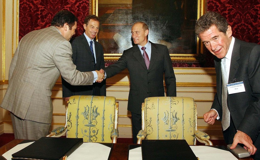 British Prime Minister Tony Blair stands aside as President Valadimir Putin of Russia, shakes hands, 26 June 2003, with Mikhail Fridman Chairman of the Alfa group, as Lord Browne (R) CEO of BP tidies up after signing a joint business deal, inside Lancaster House in London, during a Russia-UK energy summit. (Photo by JOHN STILLWELL/AFP via Getty Images) British Prime Minister Tony Blair stands aside as President Valadimir Putin of Russia, shakes hands, 26 June 2003, with Mikhail Fridman Chairman of the Alfa group, as Lord Browne (R) CEO of BP tidies up after signing a joint business deal, inside Lancaster House in London, during a Russia-UK energy summit. (Photo by JOHN STILLWELL/AFP via Getty Images)