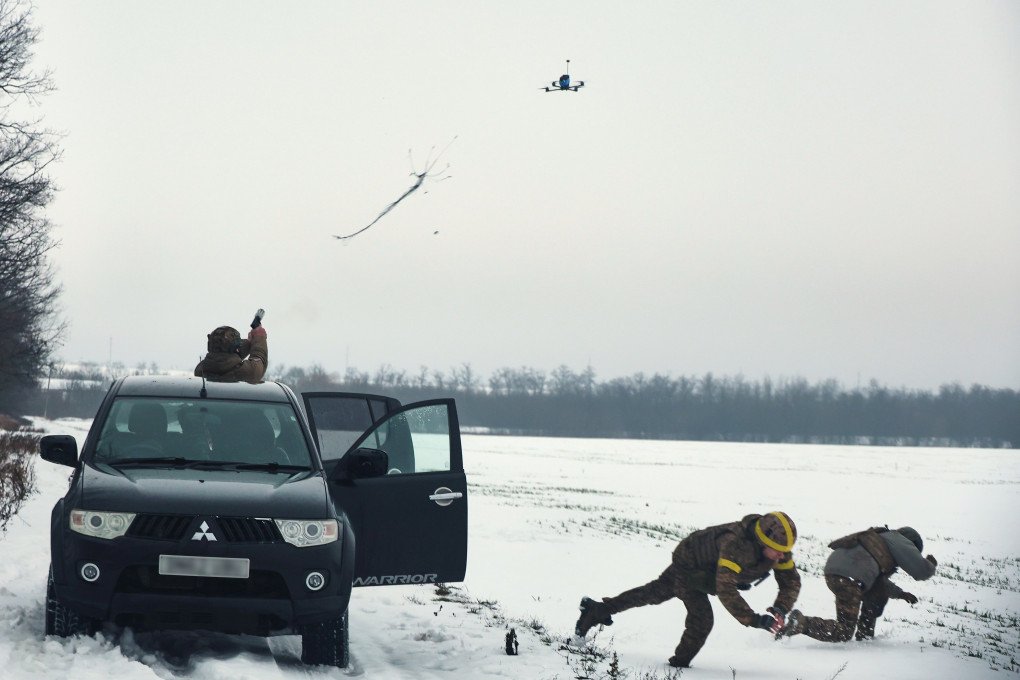 A soldier from the 13th Khartiia Brigade of Ukraine’s National Guard shoots a net gun at an FPV drone from an SUV as his fellow servicemen take cover during tests in Ukraine on January 7, 2026. (Photo: Viacheslav Madiievskyi/Ukrinform/NurPhoto via Getty Images) net gun at an FPV drone
