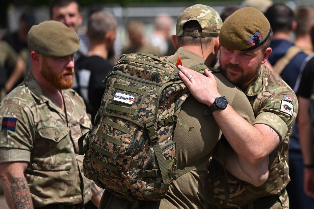 Ukrainian soldiers are embraced by British troops as they prepare to leave, having taken part in a training excercise operated by Britain's armed forces as part of the Interflex programme, in eastern England, on June 17, 2025. (Photo by Justic Tallis via Getty Images)