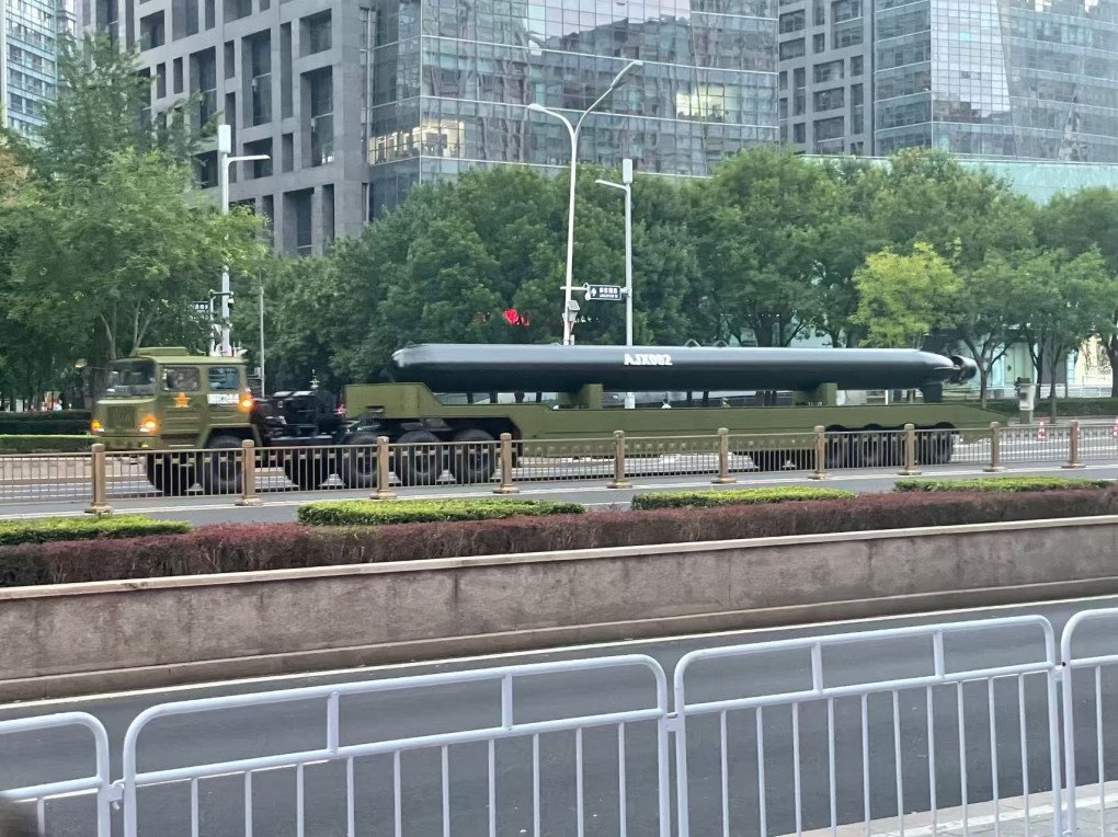 Chinese military truck transports an oversized underwater drone labeled AJX002 through a city street during parade preparations. (Photo: Open source)