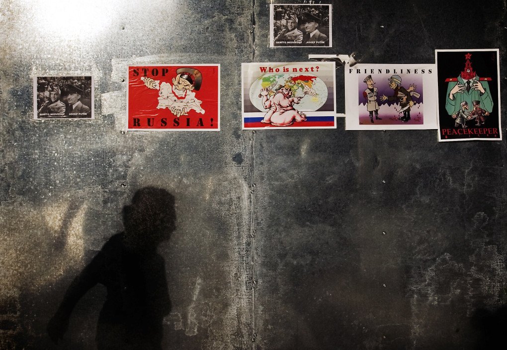 A Georgian woman casts her shadow as she walks past nationalistic posters depicting Russia’s aggression on Georgia, on August 18, 2008. Photo by Marco Longari/AFP via Getty Images.
