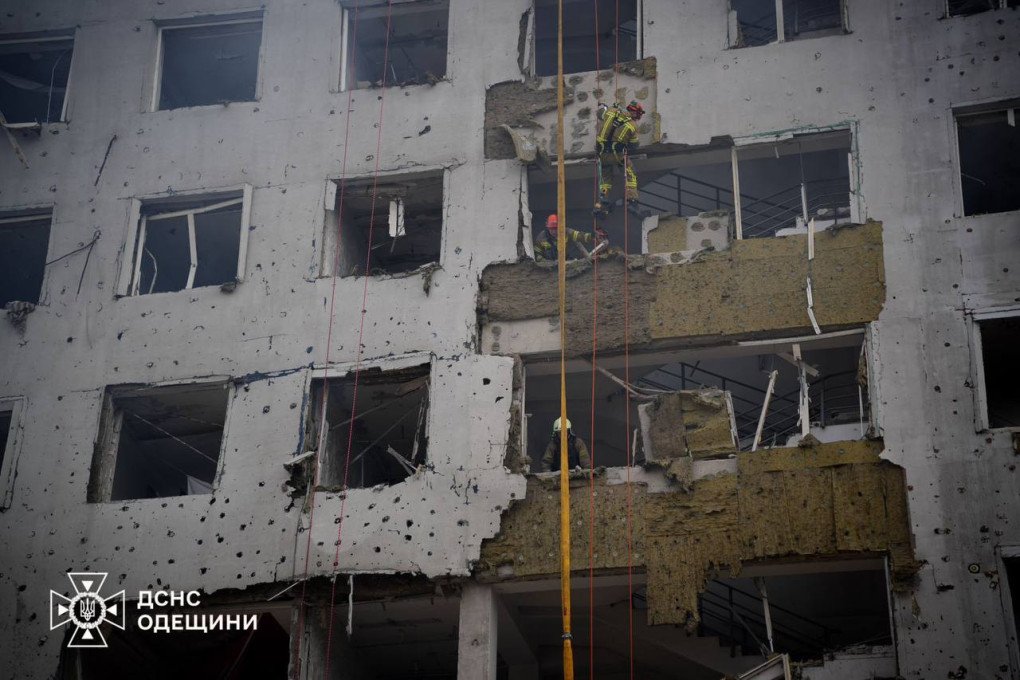 Rescatistas suspendidos con cuerdas inspeccionan edificio devastado en Odesa tras bombardeo ruso y explosión en zona urbana.