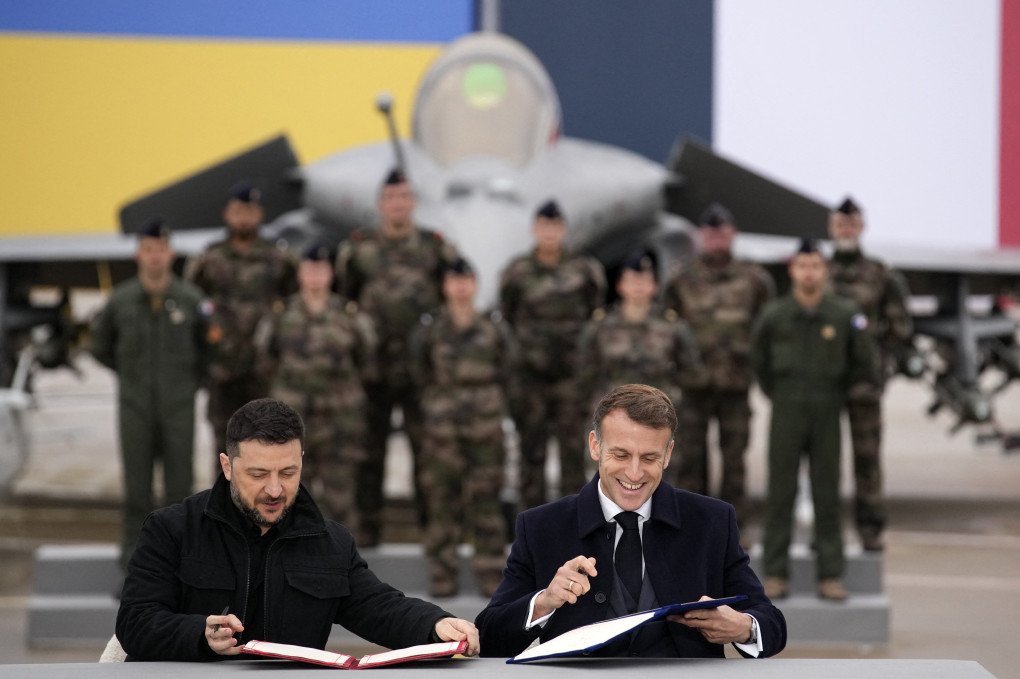 France's President Emmanuel Macron (R) and Ukraine's President Volodymyr Zelenskyy (L) sign an agreement at the Villacoublay air base, in Velizy-Villacoublay, near Paris on November 17, 2025. Macron and Zelensky signed an arms agreement at an airbase near Paris, which the Ukrainian president described as "historic" to "strengthen" Ukraine's combat aviation and air defense. (Photo by CHRISTOPHE ENA/POOL/AFP via Getty Images) France's President Emmanuel Macron (R) and Ukraine's President Volodymyr Zelenskyy (L) sign an agreement at the Villacoublay air base, in Velizy-Villacoublay, near Paris on November 17, 2025. Macron and Zelensky signed an arms agreement at an airbase near Paris, which the Ukrainian president described as "historic" to "strengthen" Ukraine's combat aviation and air defense. (Photo by CHRISTOPHE ENA/POOL/AFP via Getty Images)