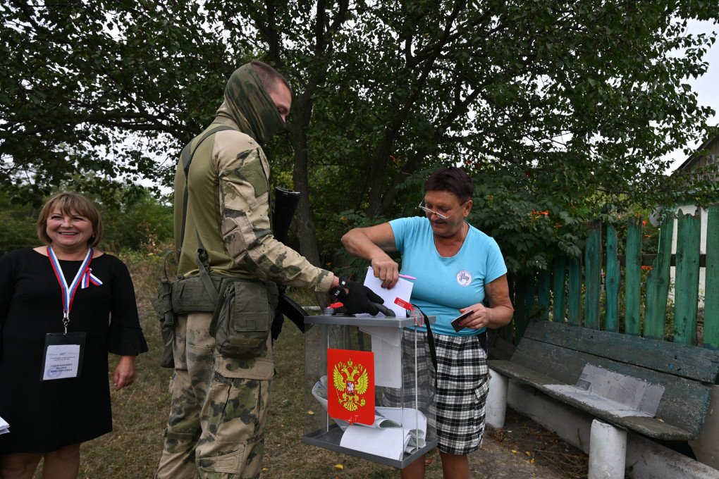 A Russian serviceman armed with a weapon accompanies members of a local election commission during early voting in Russia’s parliamentary election in the settlement of Verbovka in the Russian-occupied Donetsk region of Ukraine, on September 14, 2026. (Photo by AFP via Getty Images)