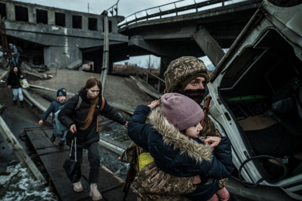A Ukrainian serviceman carries child across a makeshift walkway over a destroyed bridge during the evacuation from the city on March 05, 2022 in Irpin, Ukraine. (Photo by Serhii Mykhalchuk/Global Images Ukraine via Getty Images)