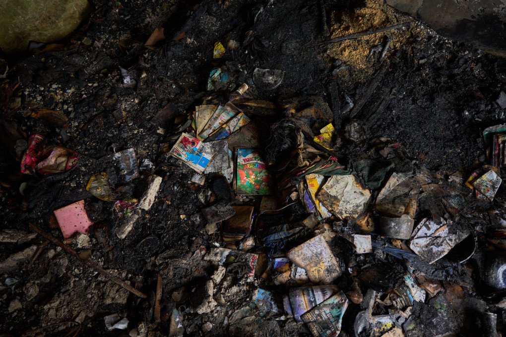 Libros infantiles carbonizados y pertenencias yacen entre las cenizas de un apartamento de Kyiv después de que el 7 de mayo de 2025 un ataque balístico y con drones ruso acabara con la vida de una madre y su hijo.