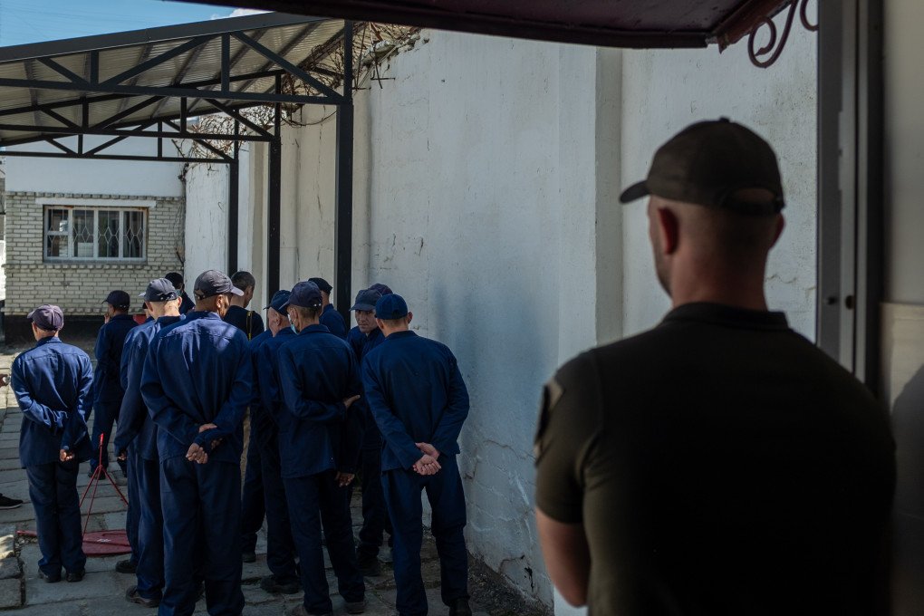 A Ukrainian guard oversees a group of Russian and foreign POWs gathered in the courtyard. Photo: Andrii Ovod/UNITED24 Media