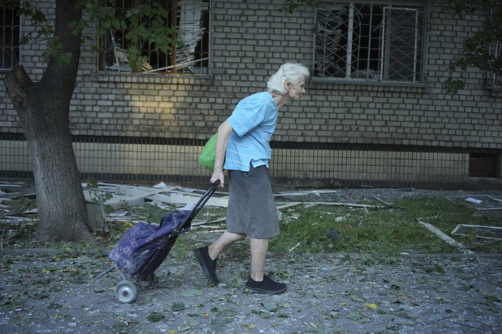 An elderly resident walks past a damaged residential building after a Russian strike, pulling a shopping cart through debris left by the attack. (Source: Lucile Brizard/UNITED24 Media) An elderly resident walks past a damaged residential building after a Russian strike, pulling a shopping cart through debris left by the attack. (Source: Lucile Brizard/UNITED24 Media)