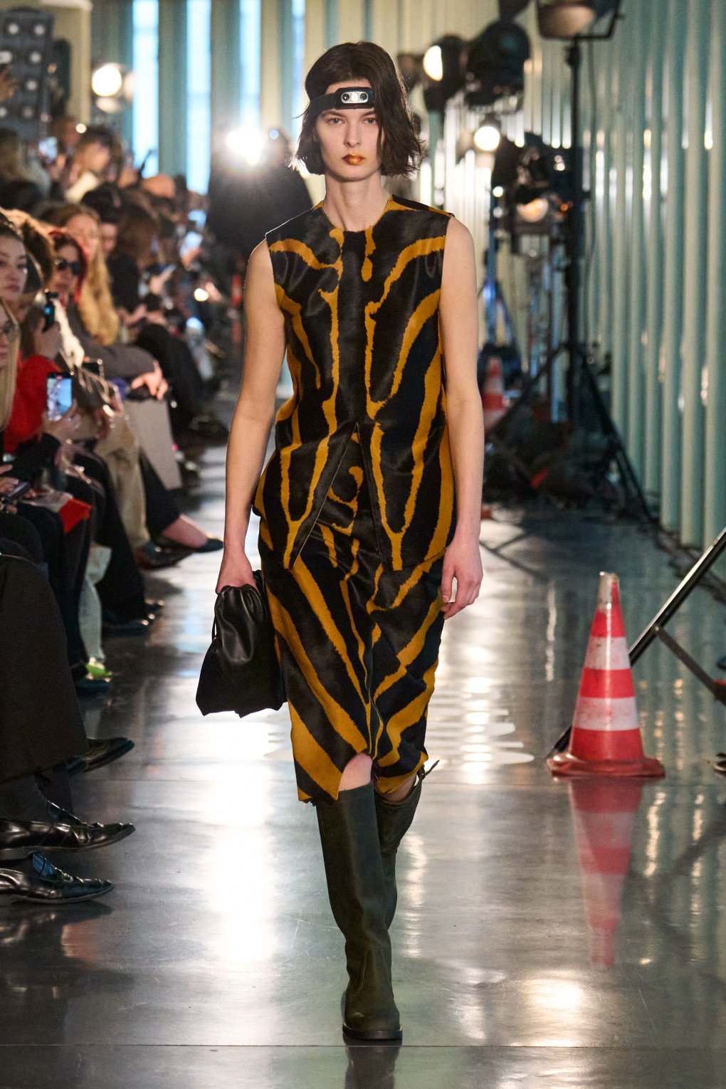 A model confidently walks the runway wearing a striking black and yellow tiger-striped dress paired with matching knee-high boots. (Source: LITKOVSKA press office)