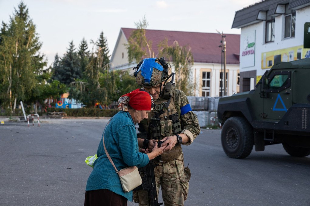 A Ukrainian soldier of the 33rd assault battalion helps a local woman fix a flashlight on August 16, 2024, in Sudzha, Russia. (Source: Getty Images)