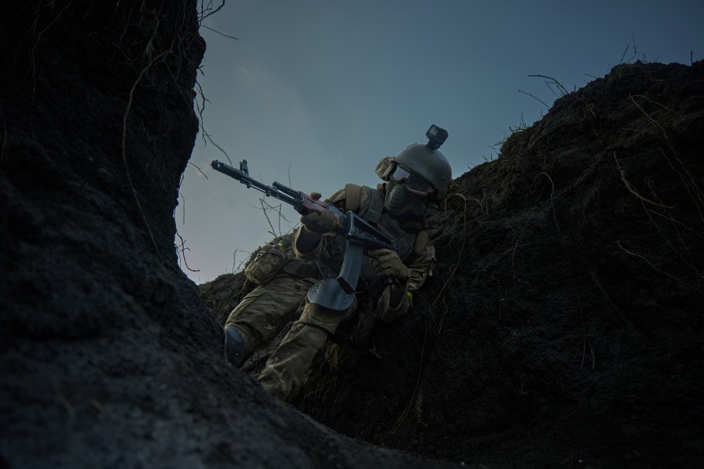 Un voluntario extranjero avanza por una estrecha trinchera durante un ejercicio de entrenamiento de combate cuerpo a cuerpo, con el arma en alto y los sentidos alerta. Un voluntario extranjero avanza por una estrecha trinchera durante un ejercicio de entrenamiento de combate cuerpo a cuerpo, con el arma en alto y los sentidos alerta.