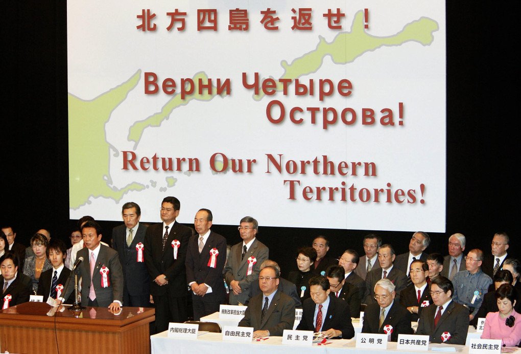 People listen to Japanese Foreign Minister Taro Aso (at the podium) deliver a speech in Tokyo, 07 February 2006, during a rally calling for the return of four Kuril islands off Japan’s northern coast seized by Moscow in 1945.