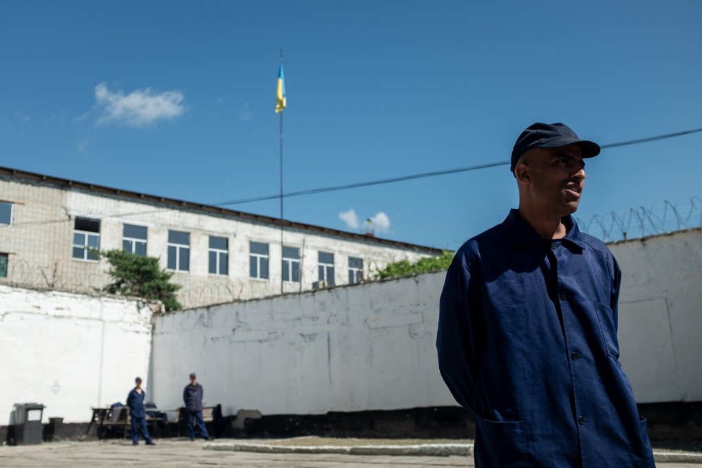 A foreign fighter captured in Ukraine stands in the prison yard, the Ukrainian flag flying above. Photo: Andrii Ovod/UNITED24 Media