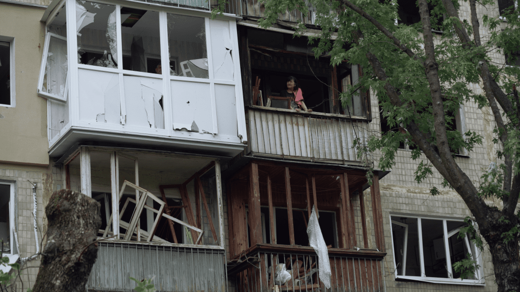 Los residentes miran desde las ventanas destrozadas de sus apartamentos destruidos. (Fuente: UNITED24 Media) Los residentes miran desde las ventanas destrozadas de sus apartamentos destruidos. (Fuente: UNITED24 Media)