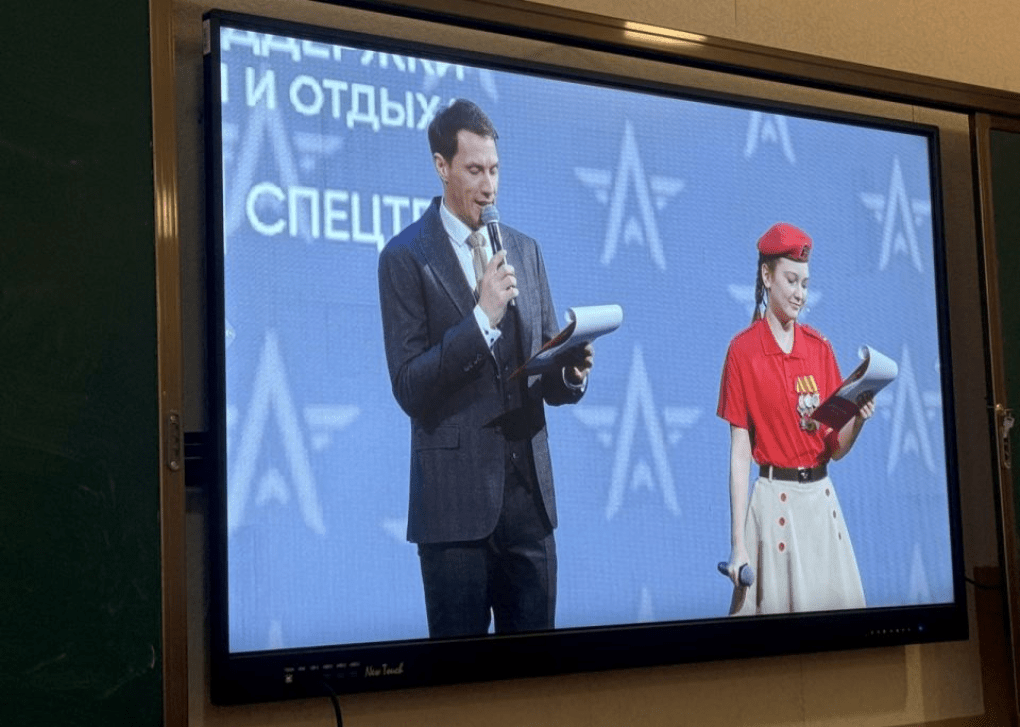 Students watched the Russia-wide broadcast, Military-patriotic dictation. Here, two hosts, one adorned in "Pioneer" style clothing (Soviet type of patriotic youth organization), are reading questions for the test. (Source: DNR News) The broadcast of the "dictation"